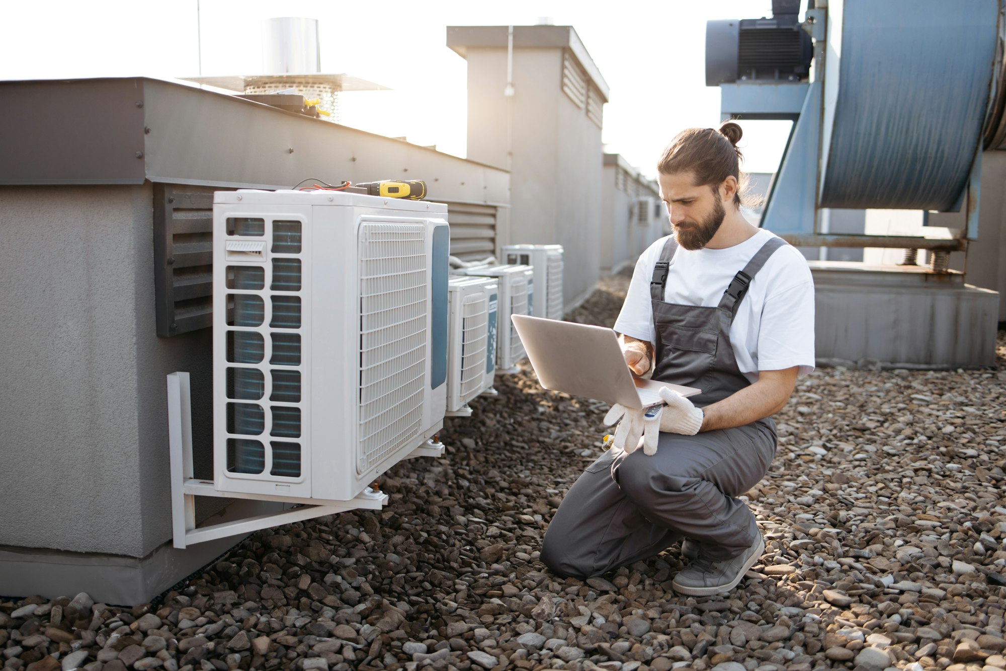 Man worker using laptop and servicing conditioner outdoor